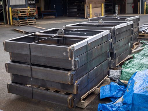 rectangular metal parts stacked on wood pallets in warehouse