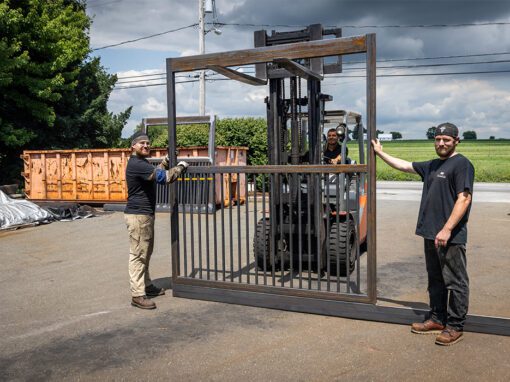 two men holding a metal horse stall on road