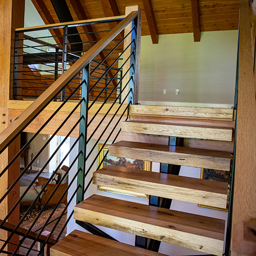 wooden floating stairs with metal railing leading to a loft