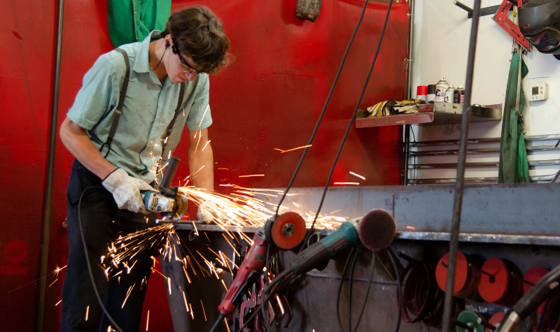 man cutting metal in metal fabrication shop